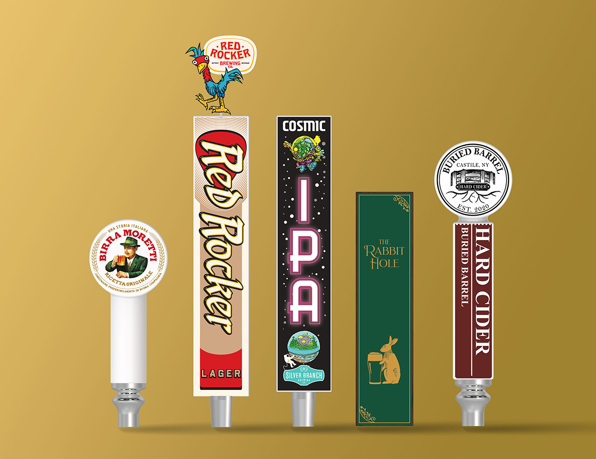 Custom beer tap handles: Birra Moretti round knob, Red Rocker Lager with rooster topper, Cosmic IPA dark handle, The Rabbit Hole green paddle, and Buried Barrel Hard Cider knob
